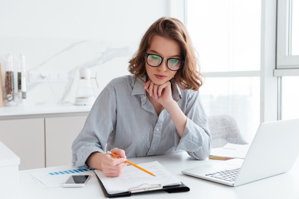 young businesswoman in glasses and a striped shirt who knows how to manage tasks diligently